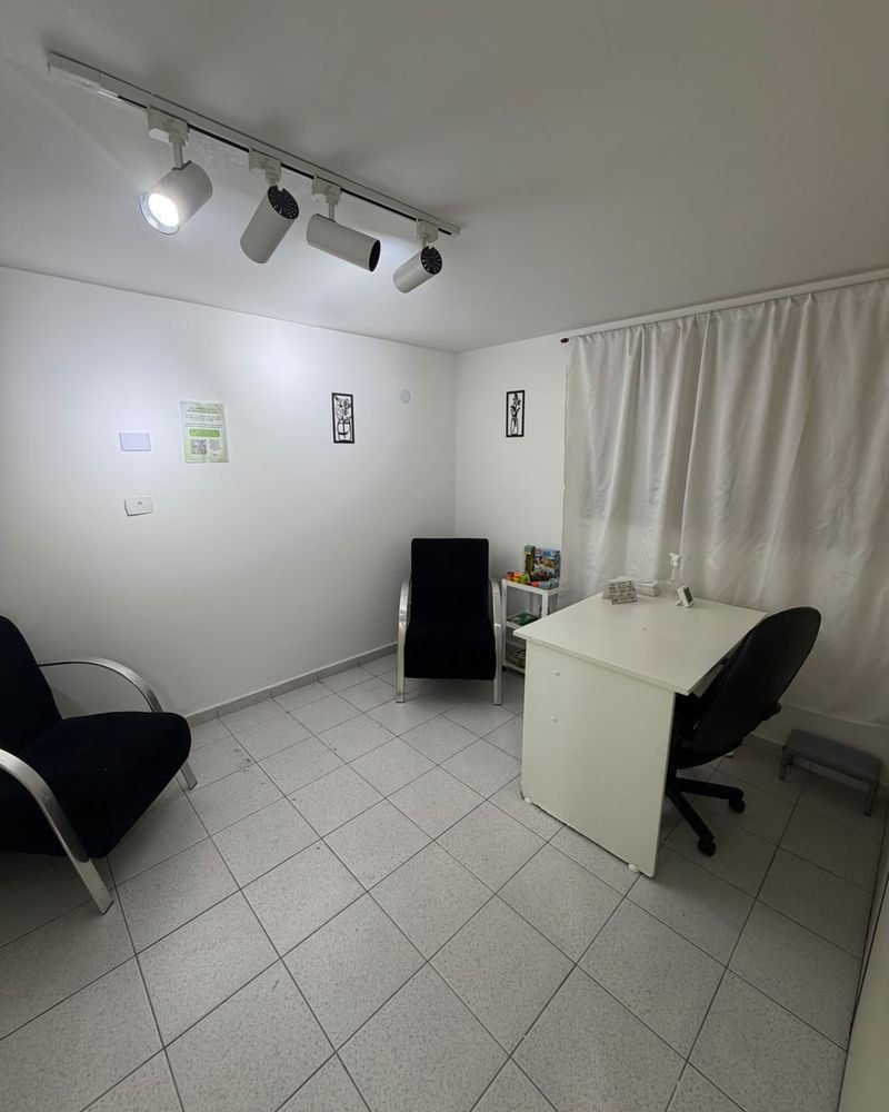 Consultório de psicologia com poltronas, mesa e brinquedos para atendimento infantil