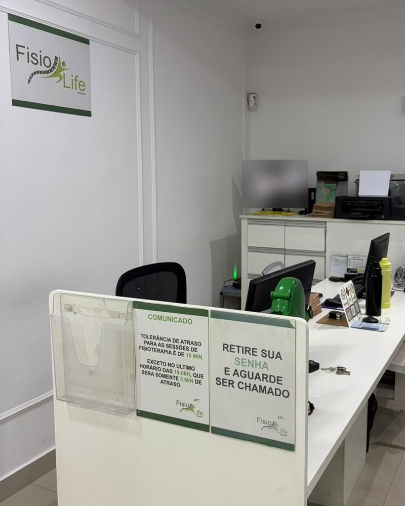 Recepção da Fisio Life com balcão de atendimento e logo da clínica na parede